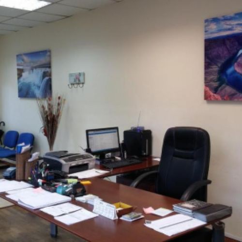 Primer plano de mesa y sillla de oficina con fotos de paisajes en las paredes